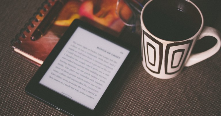 Ereader, coffee and notebook on table