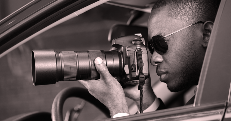 Man in car with camera and sunglasses